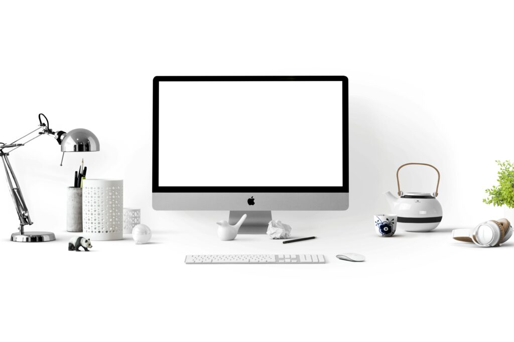 Minimalist office desk with an iMac, lamp, and stationary, perfect for tech backgrounds.